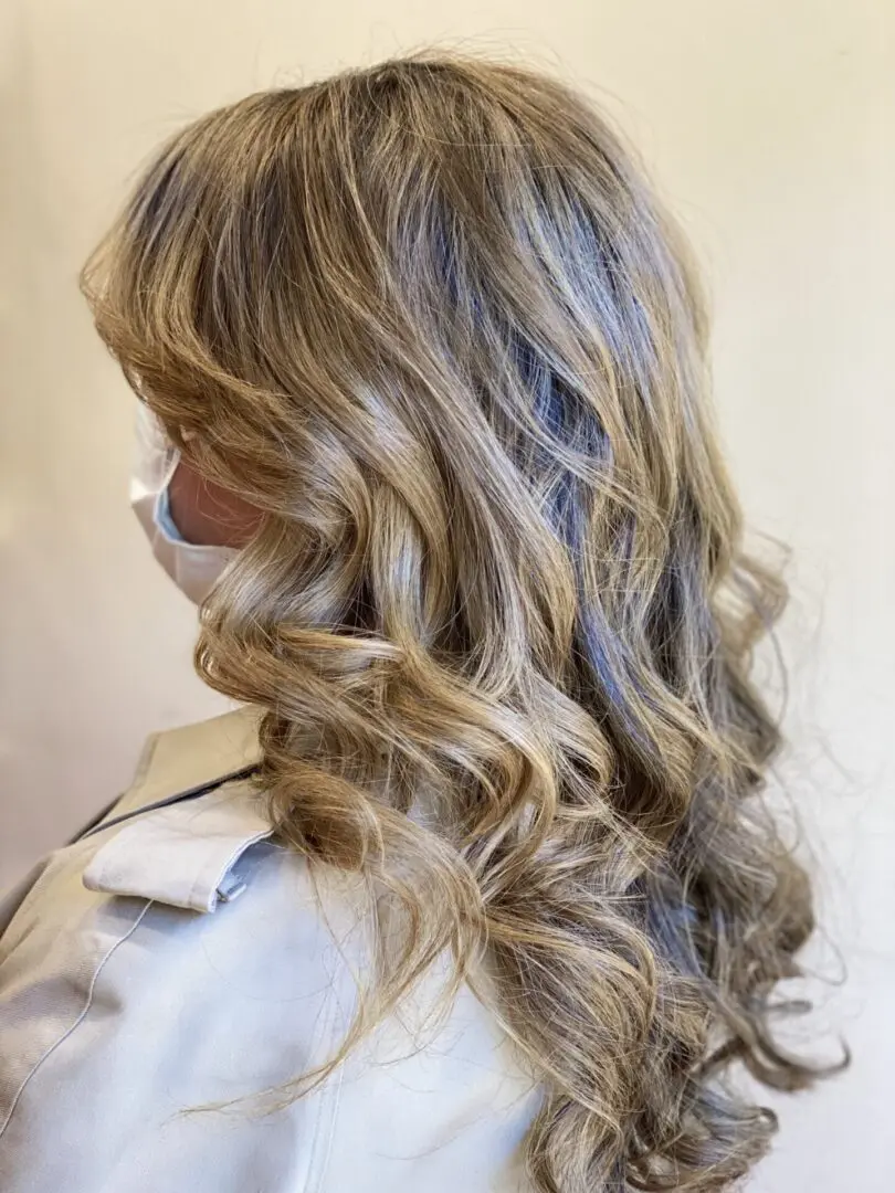 blonde curly hair of a woman wearing a mask